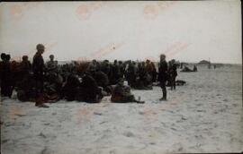 Refugiados republicanos españoles esperan sobre la arena  del Campo de concentración de Argelés en Canet Plage (Pyrenees Orientales), 1939.  Perteneciente a un conjunto de fotografías de la llegada de refugiados españoles republicanos al Campo de concentración de Argelés al finalizar la Guerra Civil española, 1939.