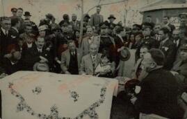 Fotografía impresa en papel postal de Mustafá Kemal, "Atatürk" (1881-1938) rodeado de personal y sentado con un niño en sus rodillas, c. 1930.